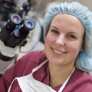 Embryologist sitting by microscope smiling | ICSI procedure with IVF | Arizona Reproductive Medicine Specialists