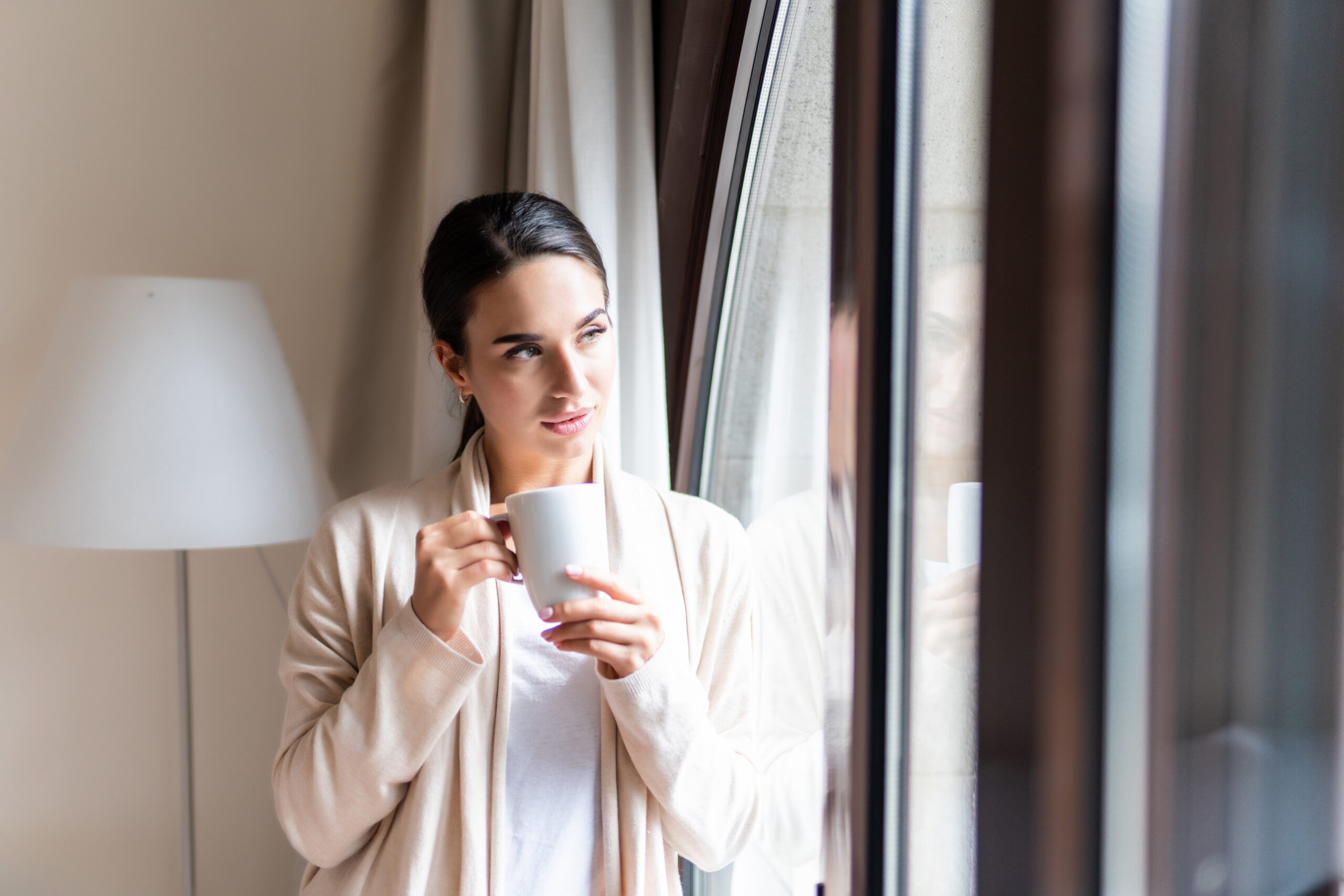 A thoughtful woman drinking coffee at home considering tubal ligation reversal | Arizona Reproductive Medicine Specialists | Phoenix