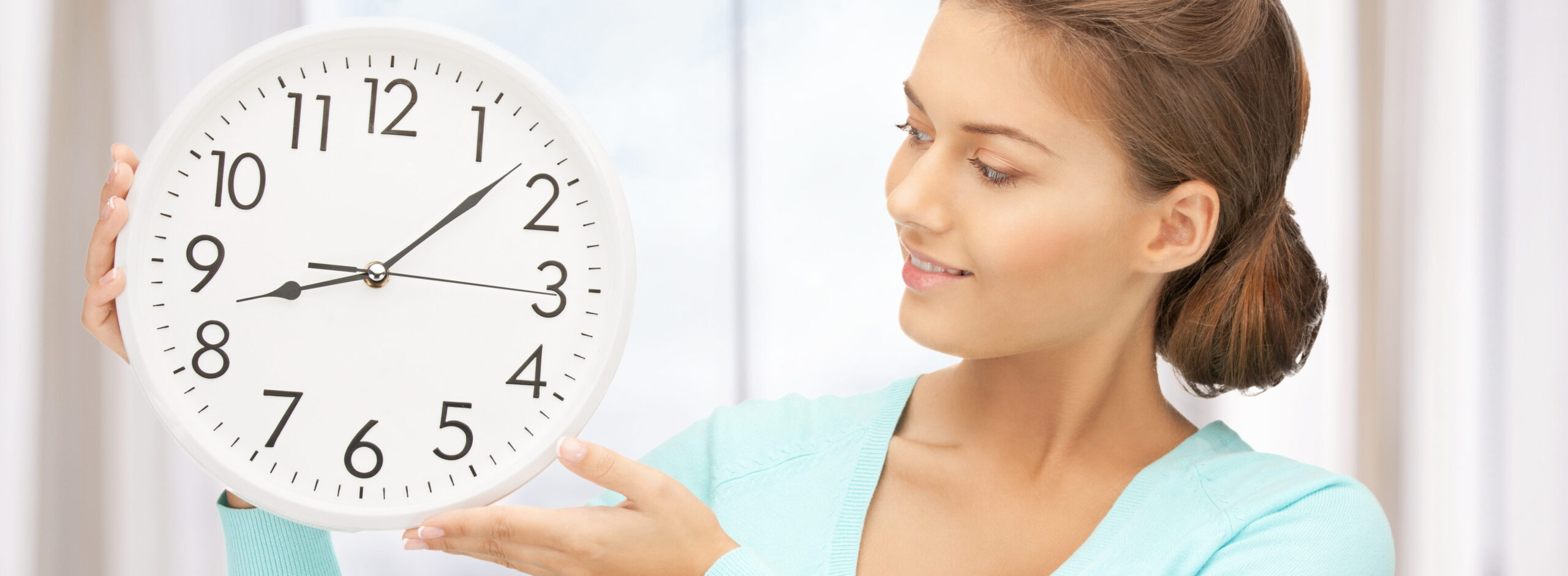 women in blue sweater holding big clock represents biology clock | Arizona Reproductive Medicine Specialists