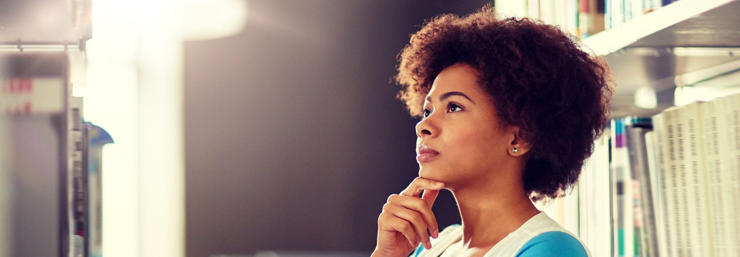 Young African American woman looking for book about uterine fibroids and infertility in the library | Arizona Reproductive Medicine Specialists