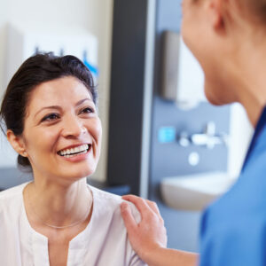 Female Patient Being Reassured By Doctor In Hospital Room
